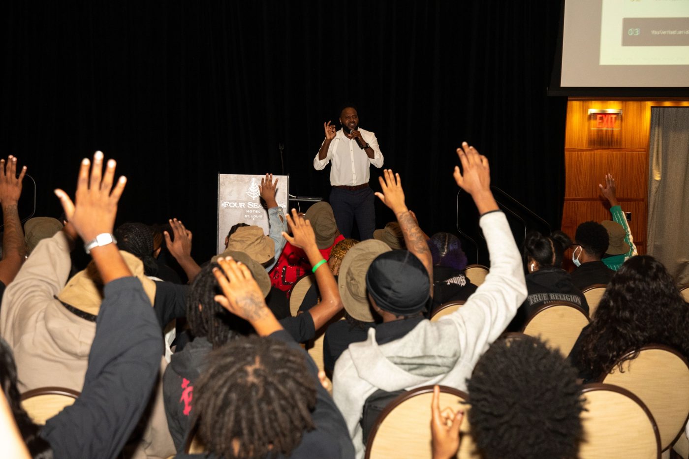Marlon on stage as a room full of young people raise their hands