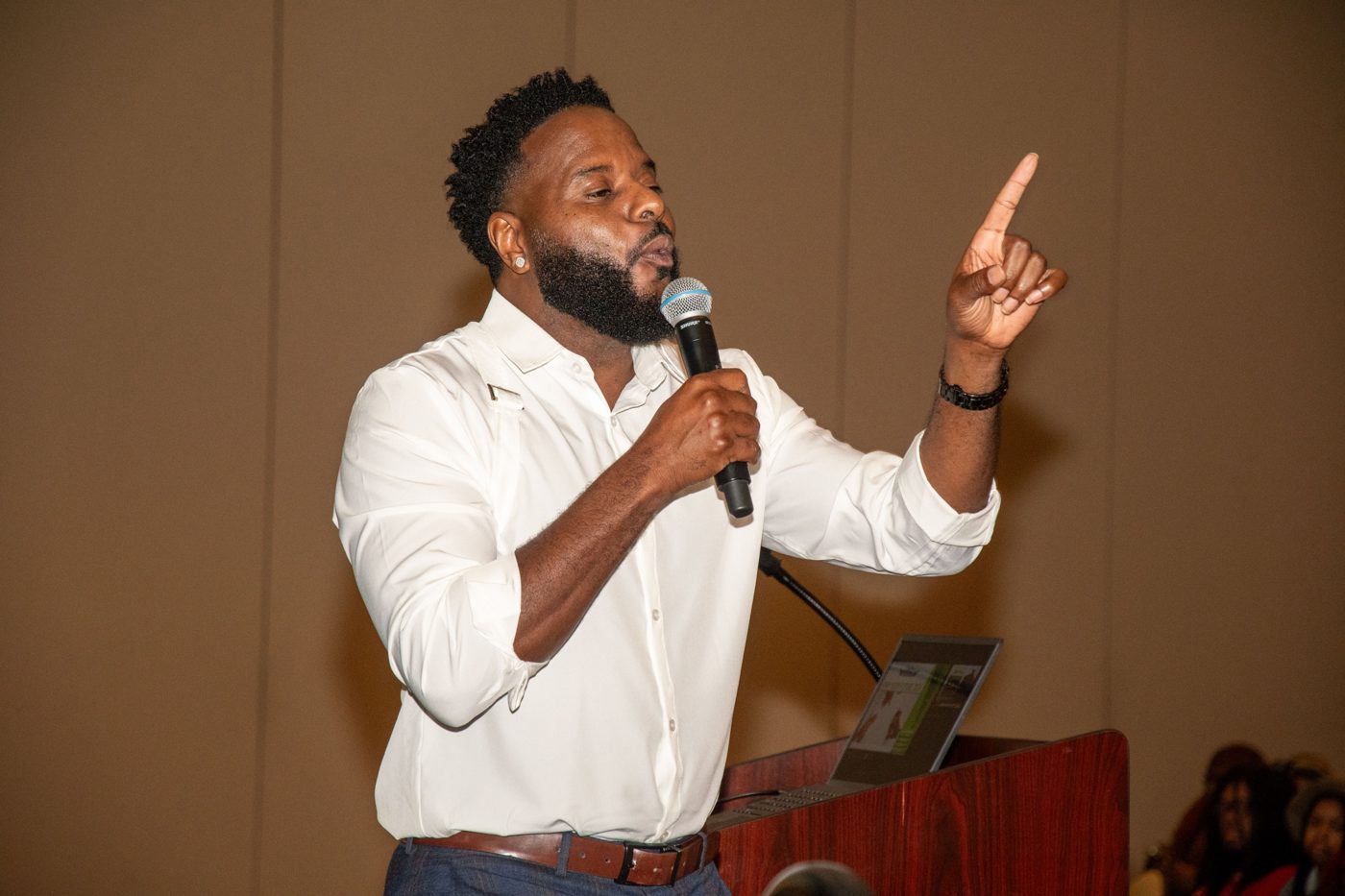 Marlon pointing upward while speaking at a podium