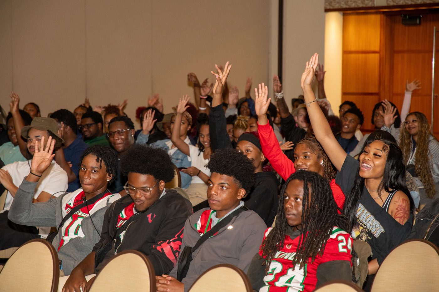 Young people in the audience raising their hands and smiling